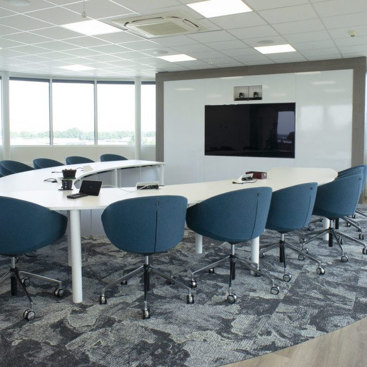 Vergaderruimte inrichting met een C-vormige vergadertafel met blauwe vergaderstoelen