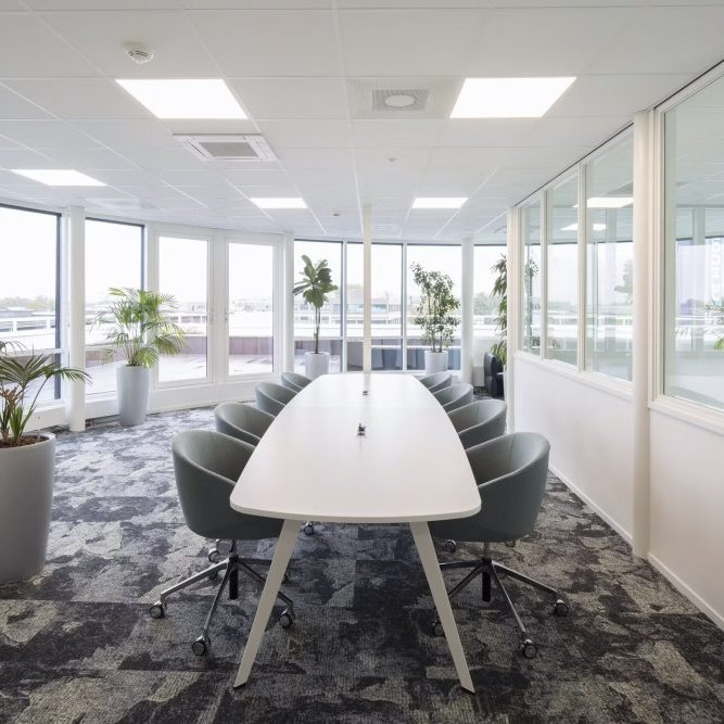 Vergaderruimte inrichting met een tonvormige vergadertafel met blauwe verrijdbare vergaderstoelen